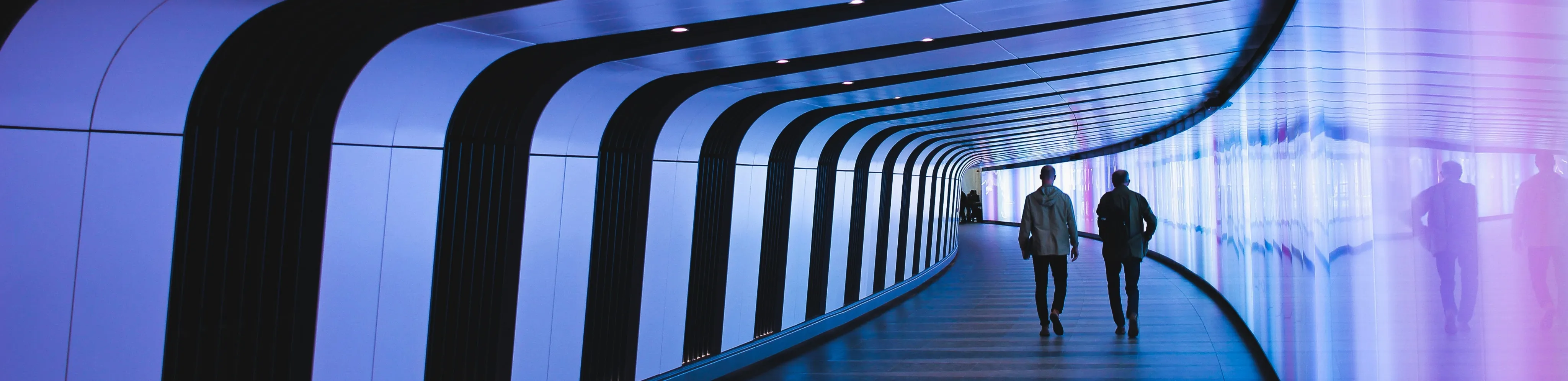 Two colleagues walking through a blue-lit corridor